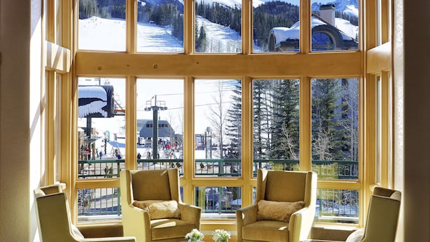 A room with large windows offering a view of a snowy mountain landscape, two armchairs, a small table with a vase, and a checkered floor. - Fairmont Heritage Place, Franz Klammer Lodge (Telluride)