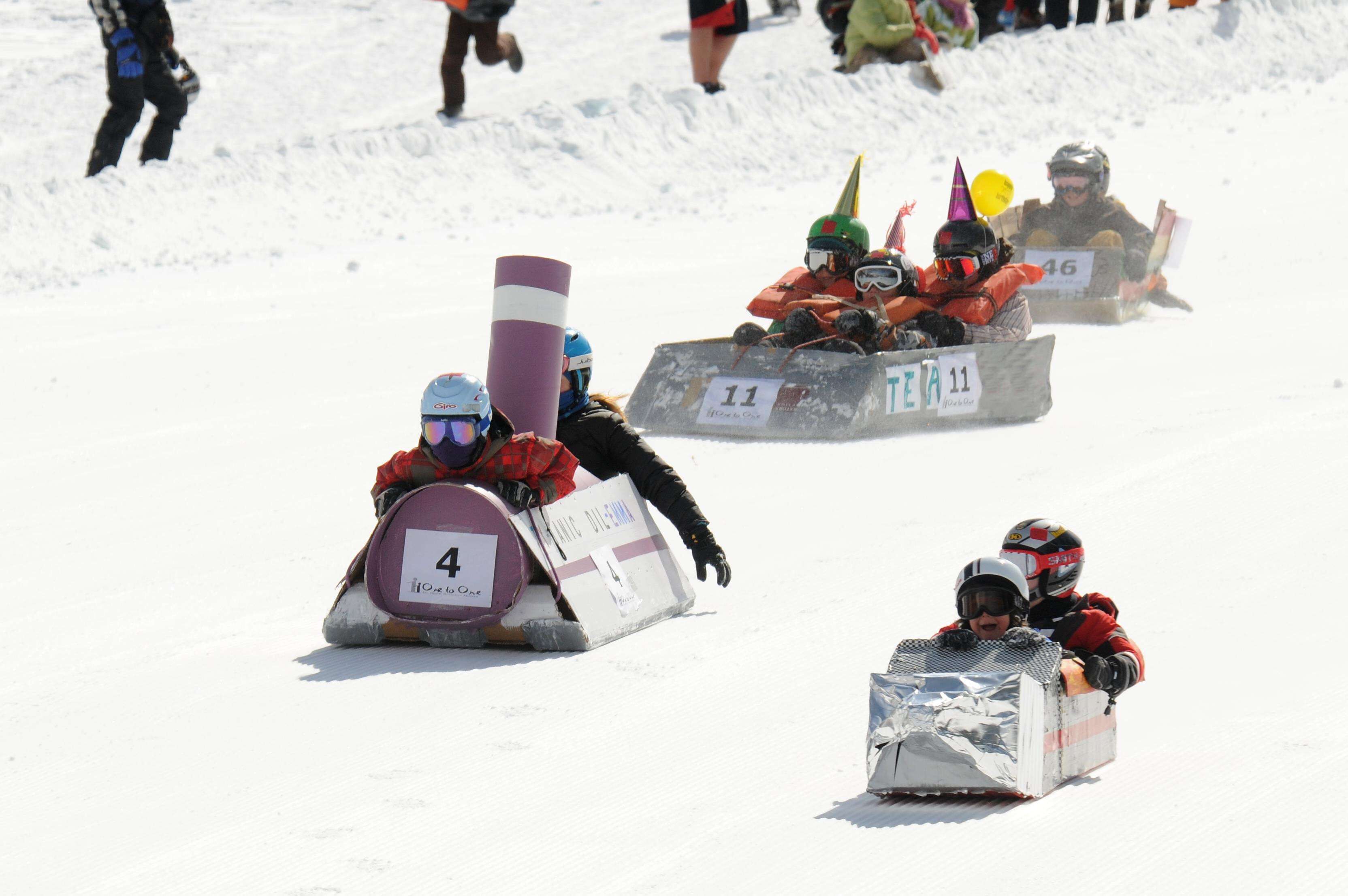 A sledding competition with participants in numbered sleds.