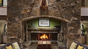 A spacious living room with a stone fireplace, leather sofas, and a central coffee table. - Fairmont Heritage Place, Franz Klammer Lodge (Telluride)