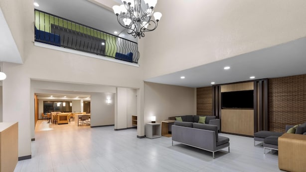 A spacious lobby with a high ceiling, a chandelier, and a seating area with sofas and a coffee table. - Hawthorn Extended Stay by Wyndham College Station South (College Station)