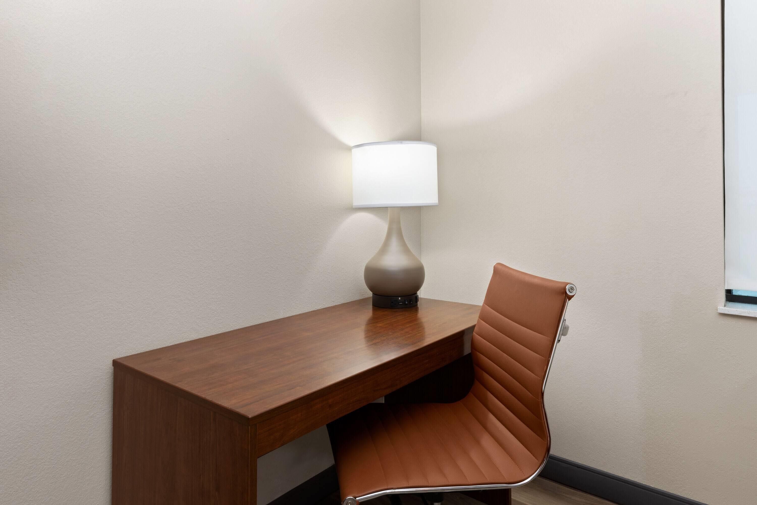 A corner desk with a lamp and a leather chair.