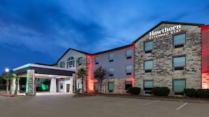 A Hawthorn Extended Stay hotel with a stone facade, multiple windows, and a covered parking area. - Hawthorn Extended Stay by Wyndham College Station South (College Station)