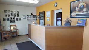 A reception area with a wooden reception desk, framed certificates on the wall, a clock, and a calendar.