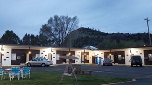 A motel with multiple rooms, a parking lot, and a grassy area with chairs.