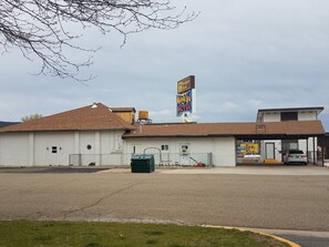 Un motel avec une enseigne, un parking délimité par une clôture et un bâtiment doté d’un toit brun.