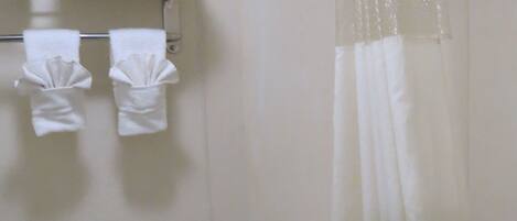 A small, clean bathroom with a toilet, a shower curtain, and a shelf with towels.