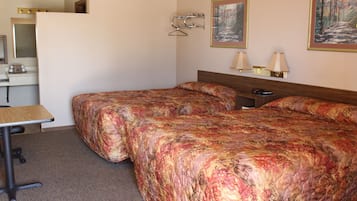 Habitación de hotel con dos camas, un escritorio, una silla, un aparador y dos lámparas fijadas a la pared.