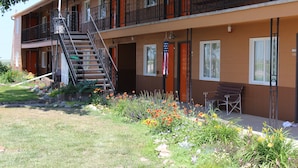 A two-story motel with a balcony, a staircase, and a flower garden in front. - Budget Host Sundowner Motor Inn (Kadoka)