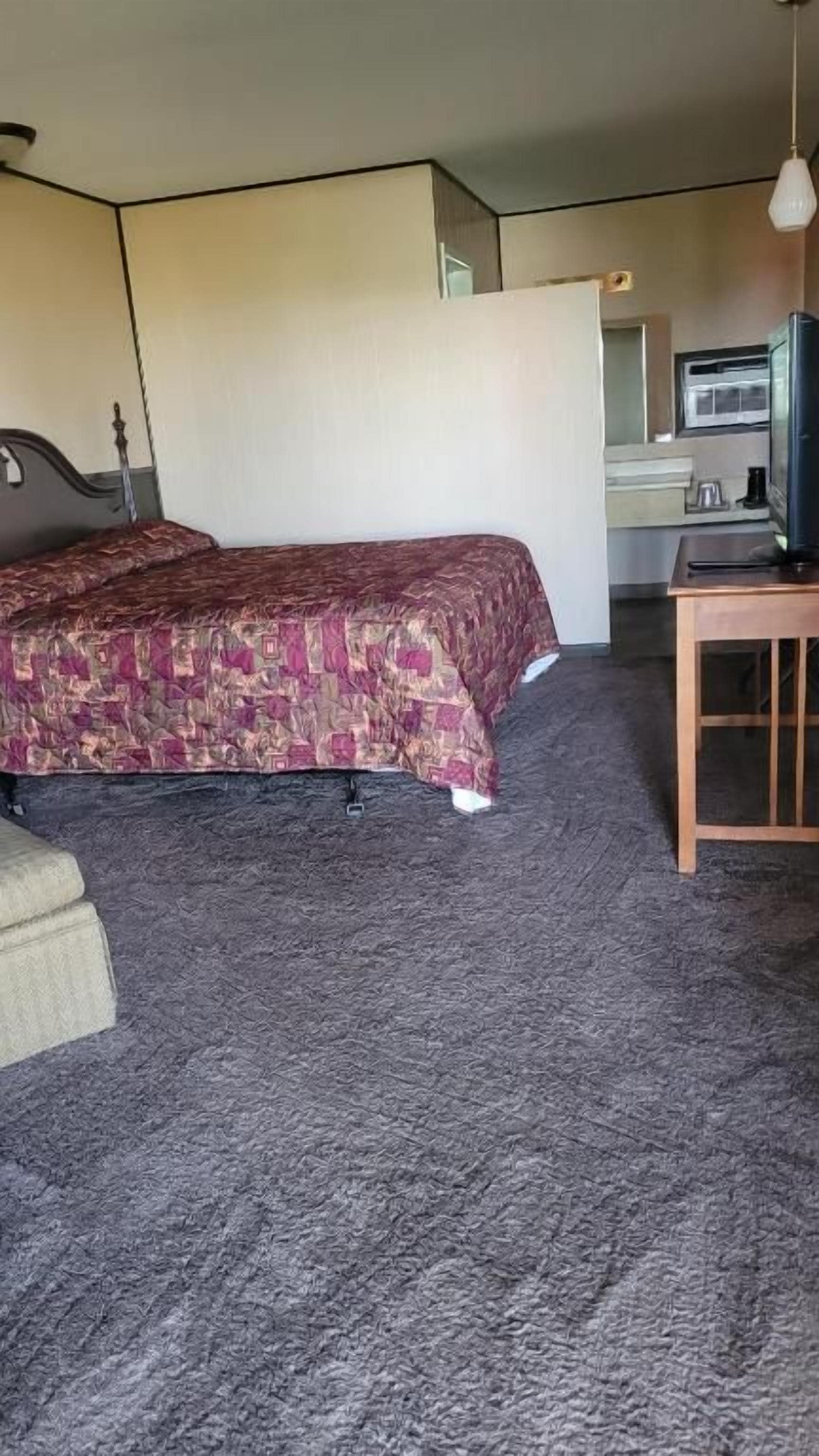 Een hotelkamer met een bed, een klein tafeltje en een televisie.