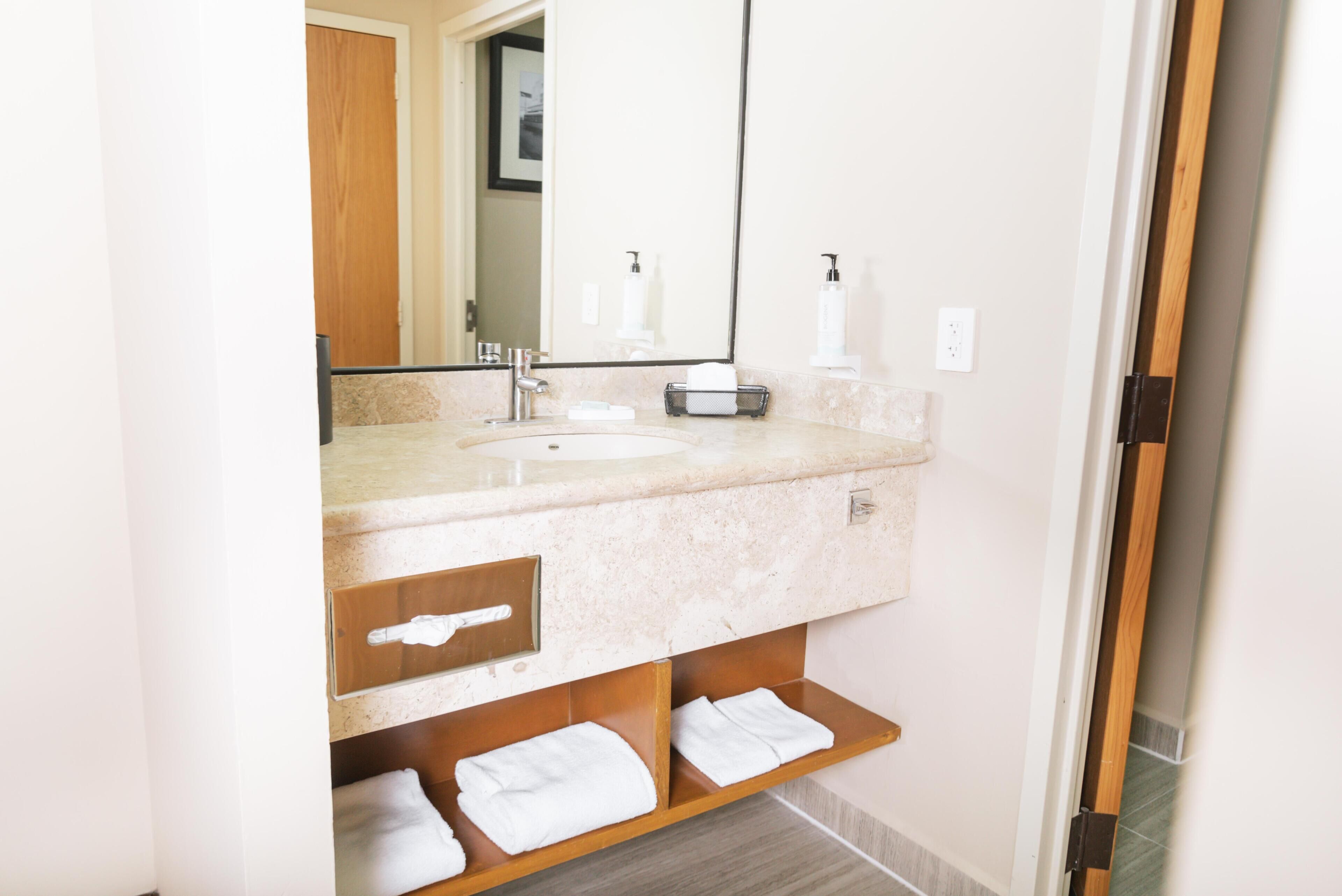 A bathroom with a sink, mirror, towel rack, and wooden shelves.