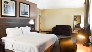 A hotel room with a large bed, a desk with a lamp, a sofa, and two framed pictures on the wall. - Hampton Inn By Hilton Tampico Zona Dorada (Tampico)