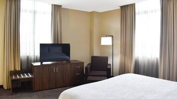 Una habitación de hotel con una cama, un televisor en un mueble de madera, una silla y un escritorio.