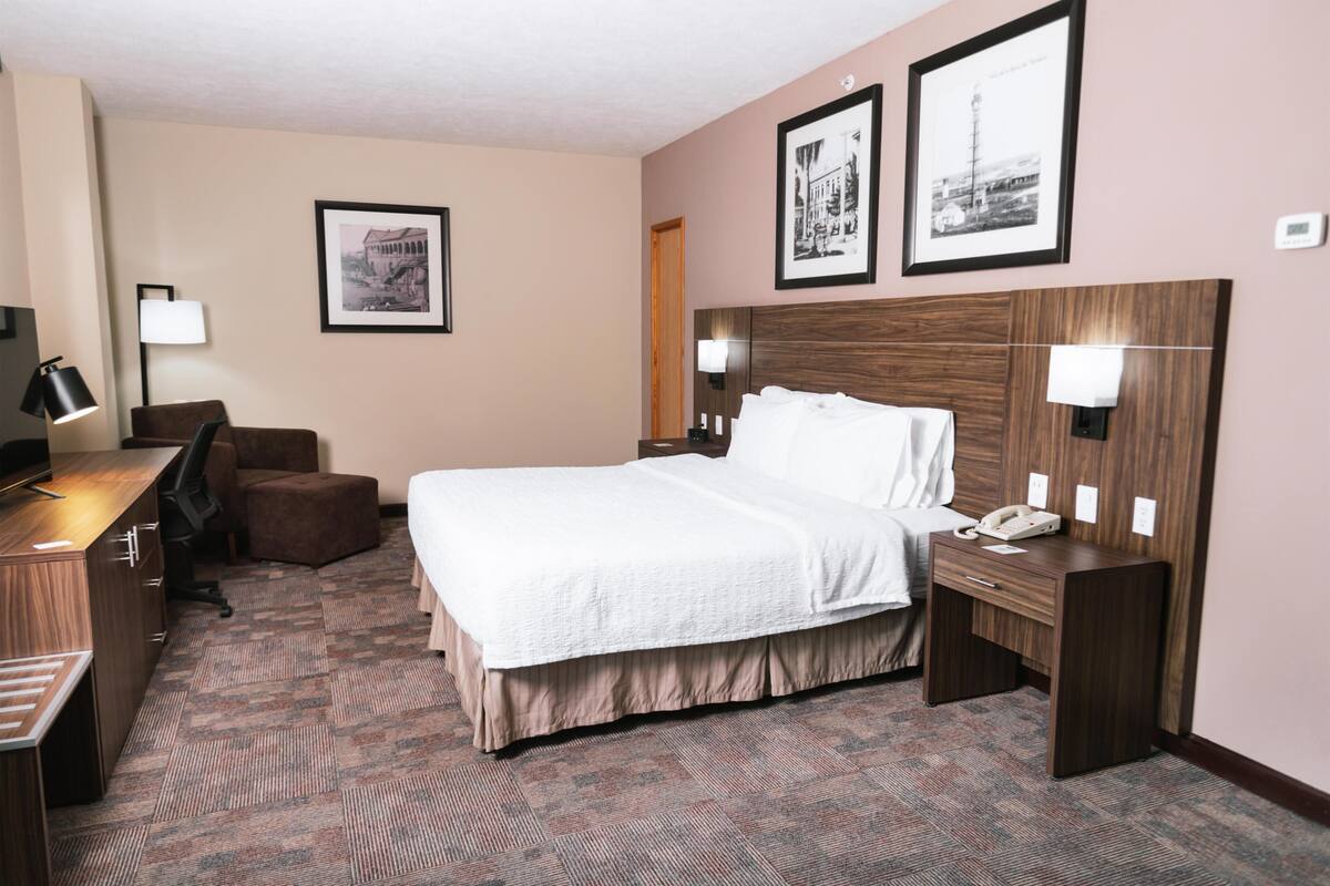 Une chambre d’hôtel équipée d’un lit, d’un bureau, d’une chaise et de deux lampes fixées au mur.