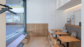 Een modern interieur met een zithoek, houten tafels en uitzicht door een groot raam.