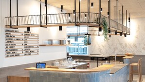 A modern kitchen with a central island, pendant lighting, and a menu board listing breakfast and drinks.