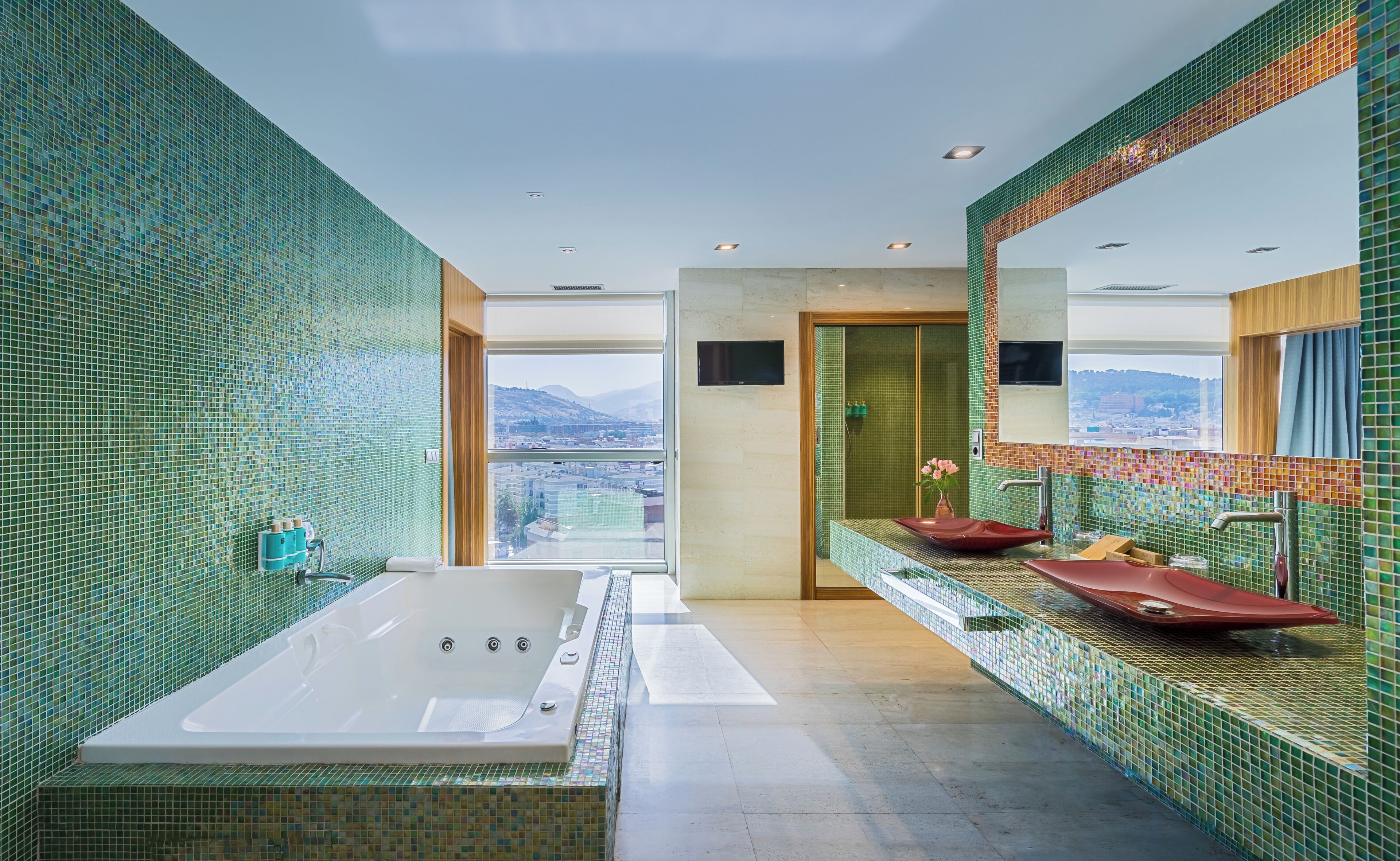 Un baño moderno con una bañera grande, dos lavamanos y vistas a la ciudad a través de un ventanal.