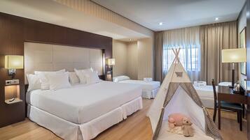 Une chambre d’hôtel avec un grand lit, un plus petit lit, un bureau et une tente indienne décorée de peluches.