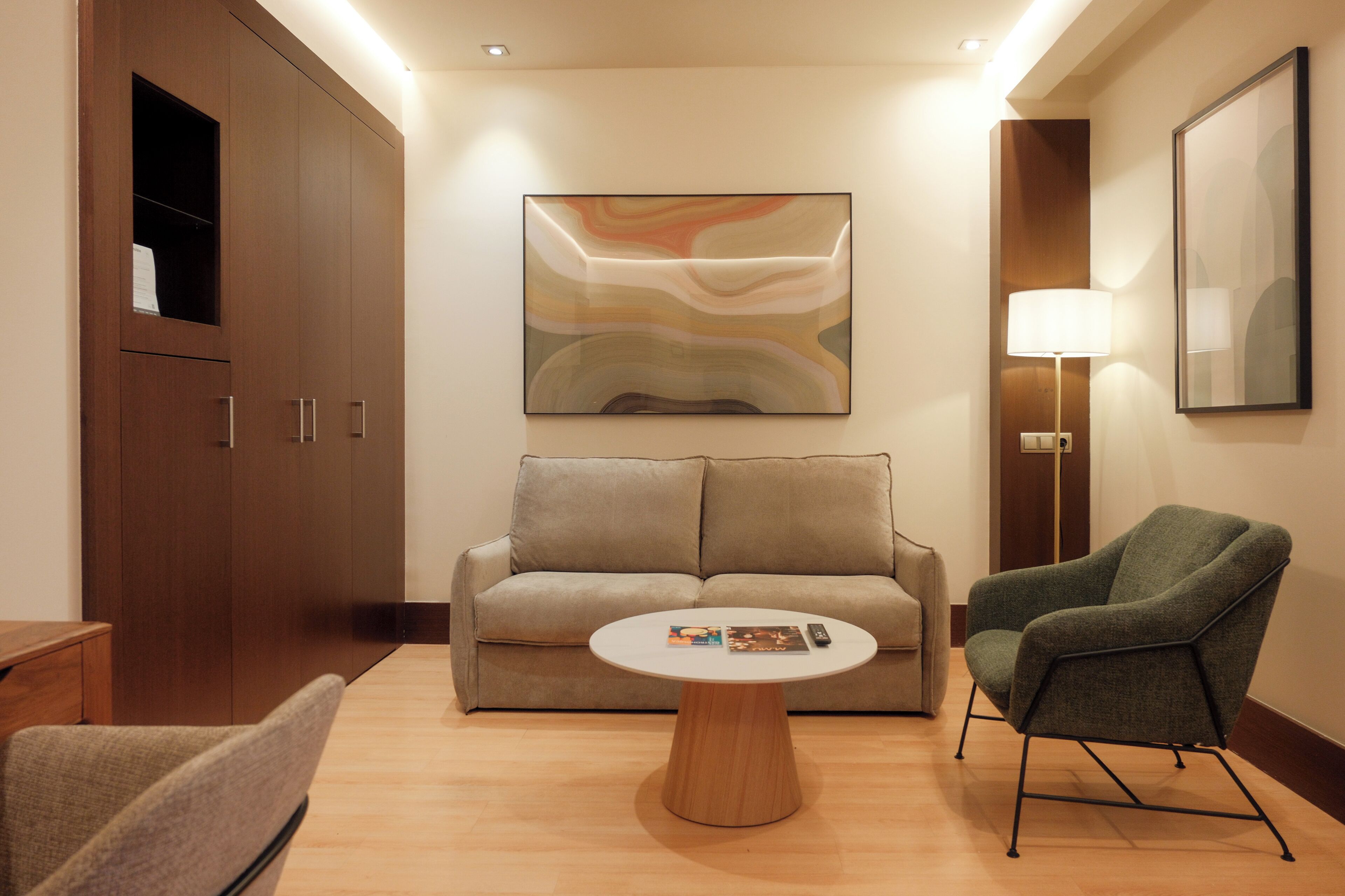 Una habitación de hotel moderna con sofá, sillón y una mesa de centro.