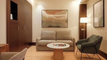 Una habitación de hotel moderna con sofá, sillón y una mesa de centro.