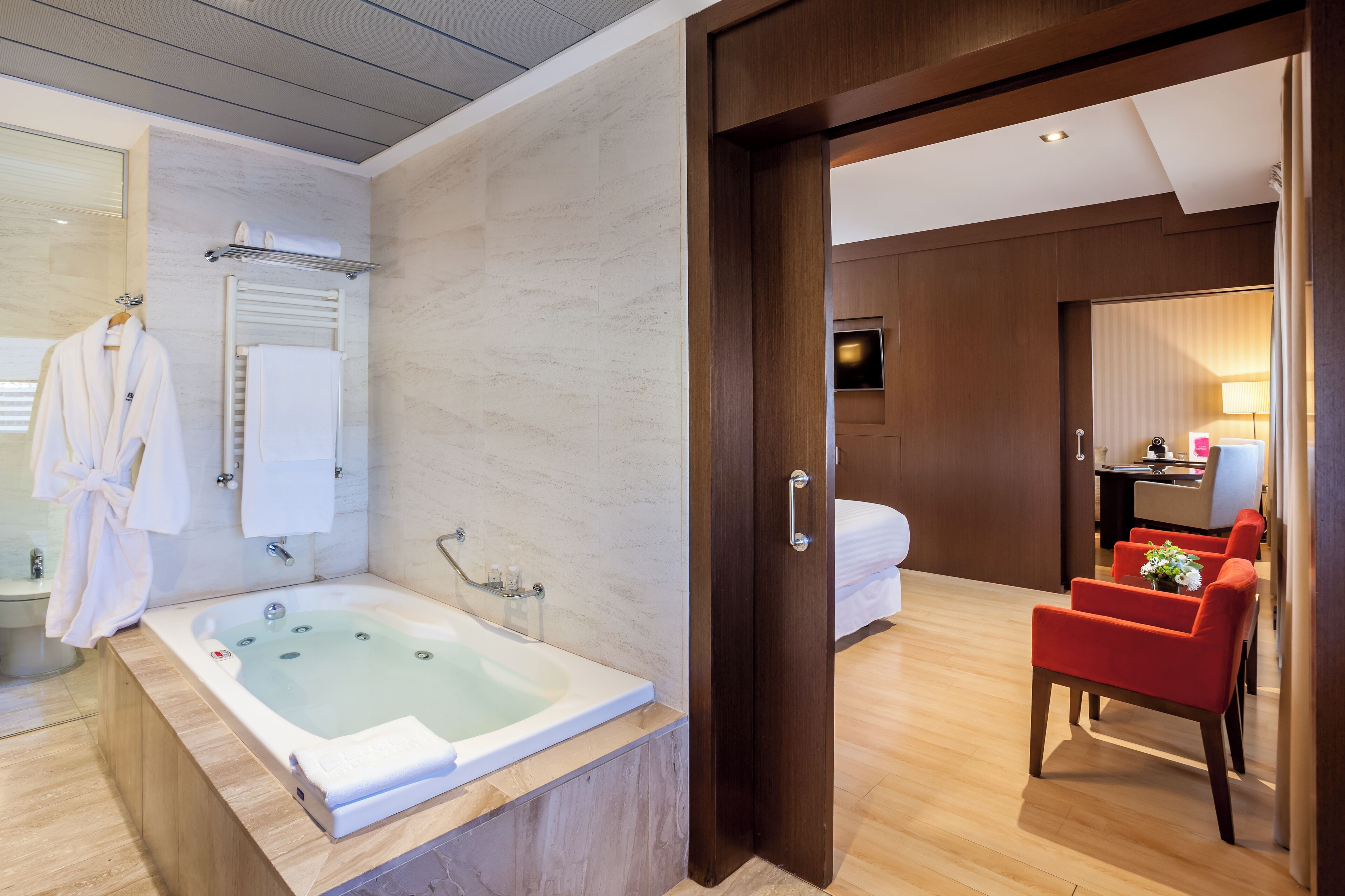 Un baño moderno con una bañera grande, un perchero y una bata colgada en la pared.
