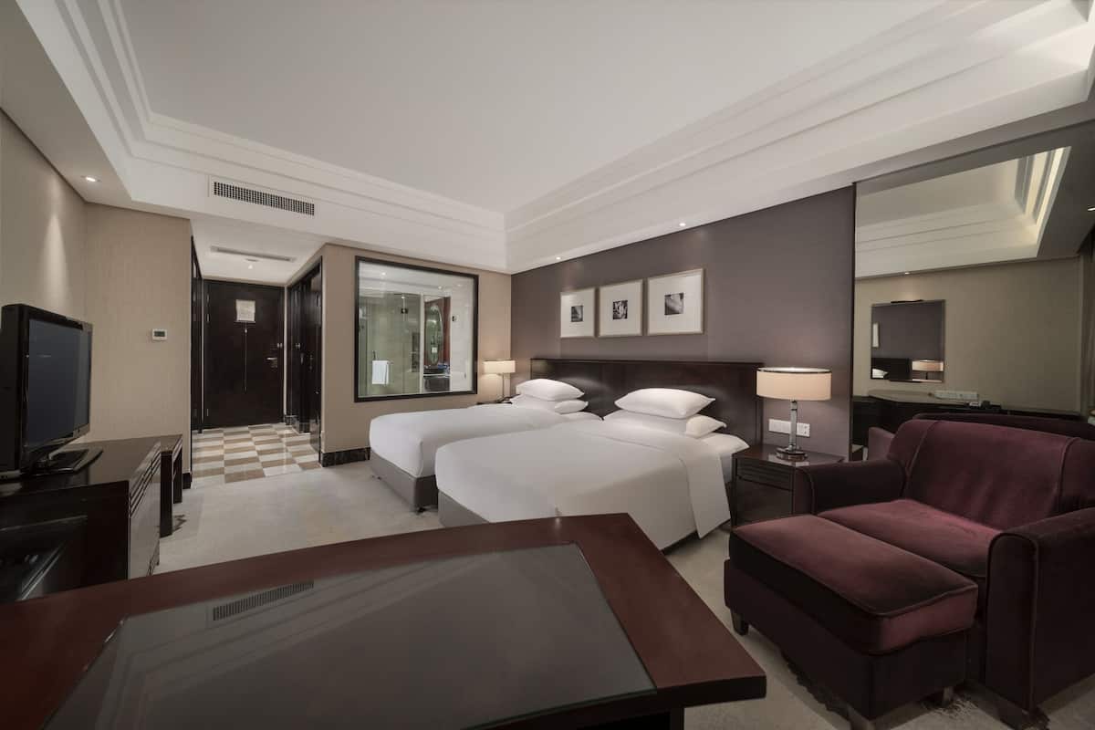 Una habitación de hotel con dos camas, televisor, escritorio y sofá.