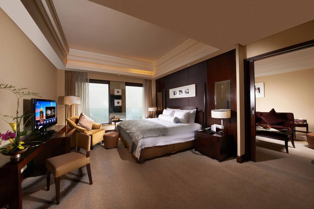 Habitación de hotel con una cama grande, un escritorio con ordenador, una silla, un sofá y un televisor.