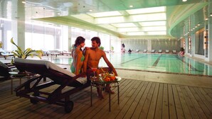 Zona junto a la piscina con sillas de descanso, una mesa con una bandeja de frutas y vistas a la piscina.
