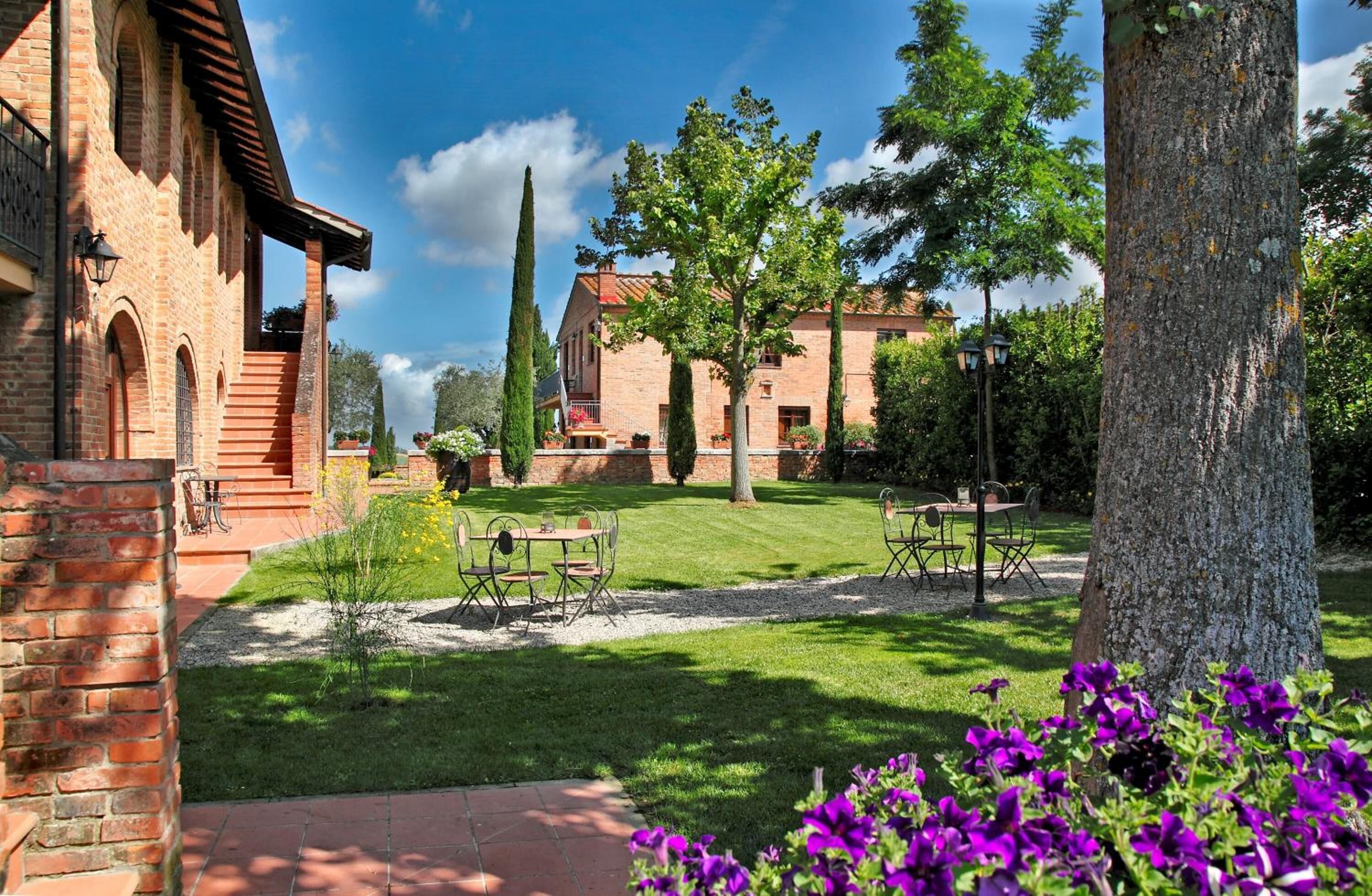 A courtyard with a brick building, outdoor seating, and a large tree.