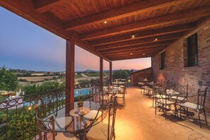 Un patio al aire libre con mesas y sillas, una piscina y vistas al campo.