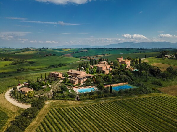 Villa rural con varias construcciones, piscina y viñedos en terrazas.