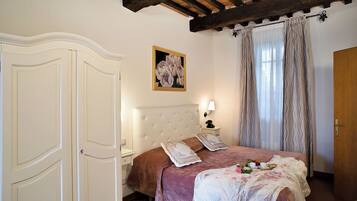 Una camera da letto con un letto grande, un comodino, una lampada a parete, un quadro e una porta in legno.