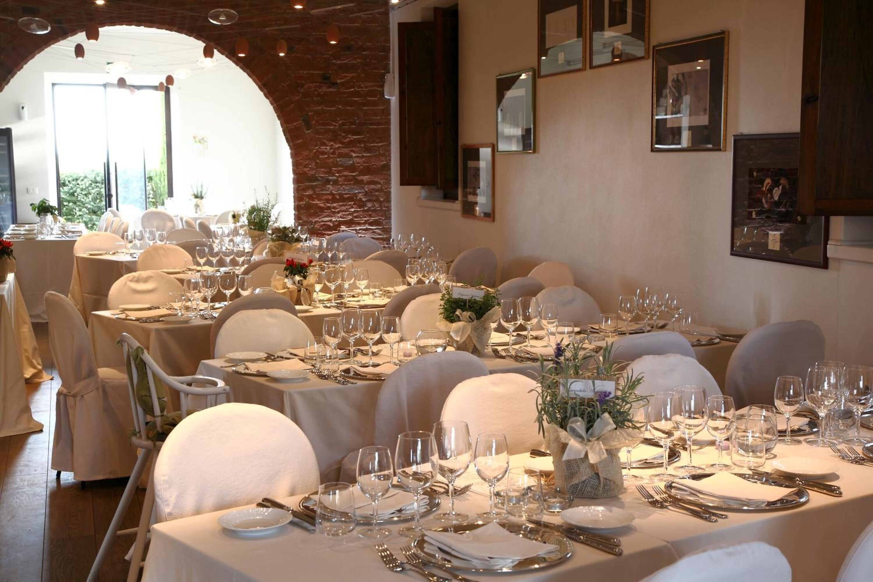 A restaurant with multiple round tables set with white tablecloths, chairs, and glassware.