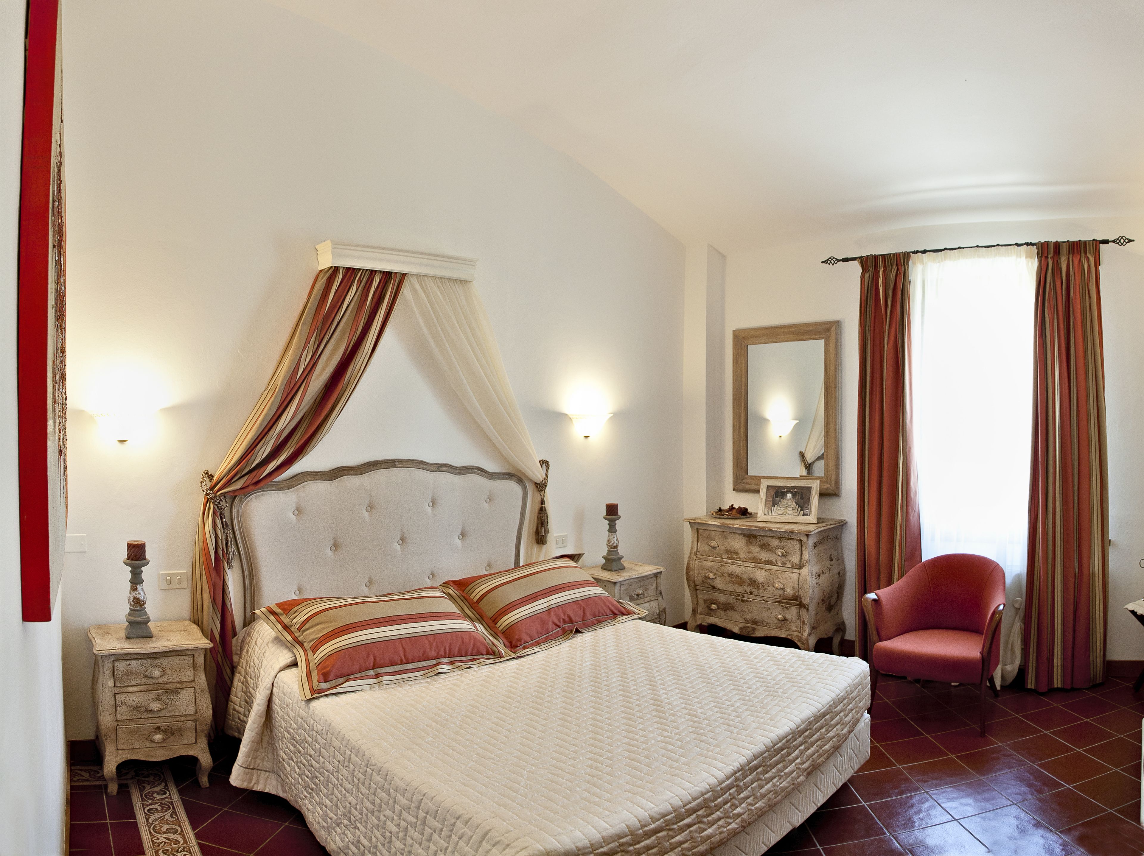 A bedroom with a four-poster bed, a nightstand, a dresser, a chair, and a mirror.