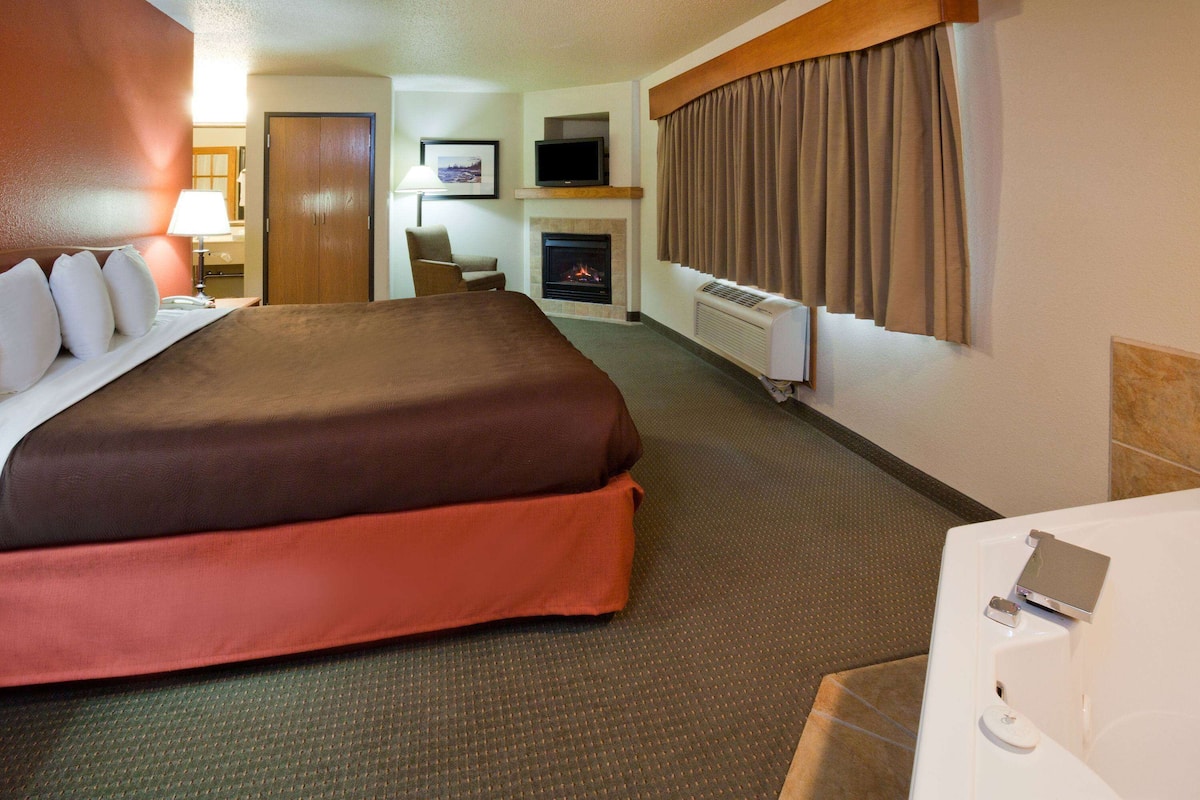 Une chambre d’hôtel avec un grand lit, une télévision, une cheminée et une salle de bain.