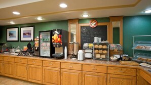 Un comptoir pour le petit-déjeuner équipé d’une machine à café, d’un réfrigérateur-vitrine et de divers produits alimentaires.