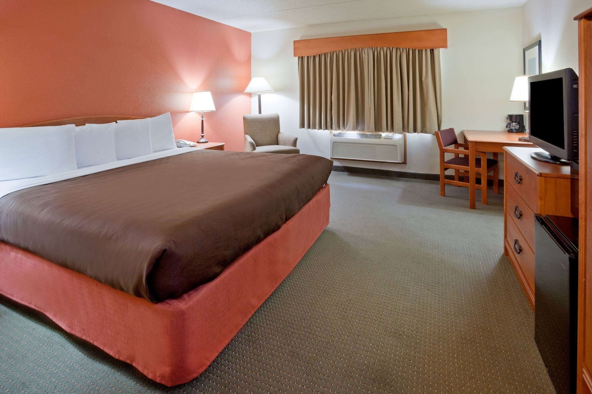 Une chambre d’hôtel avec un grand lit, un bureau avec une chaise, une télévision et un appareil de climatisation.