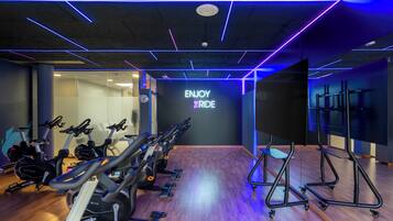 Gimnasio con bicicletas estáticas, cintas de correr y una pared con el texto 'ENJOY THE RIDE'.