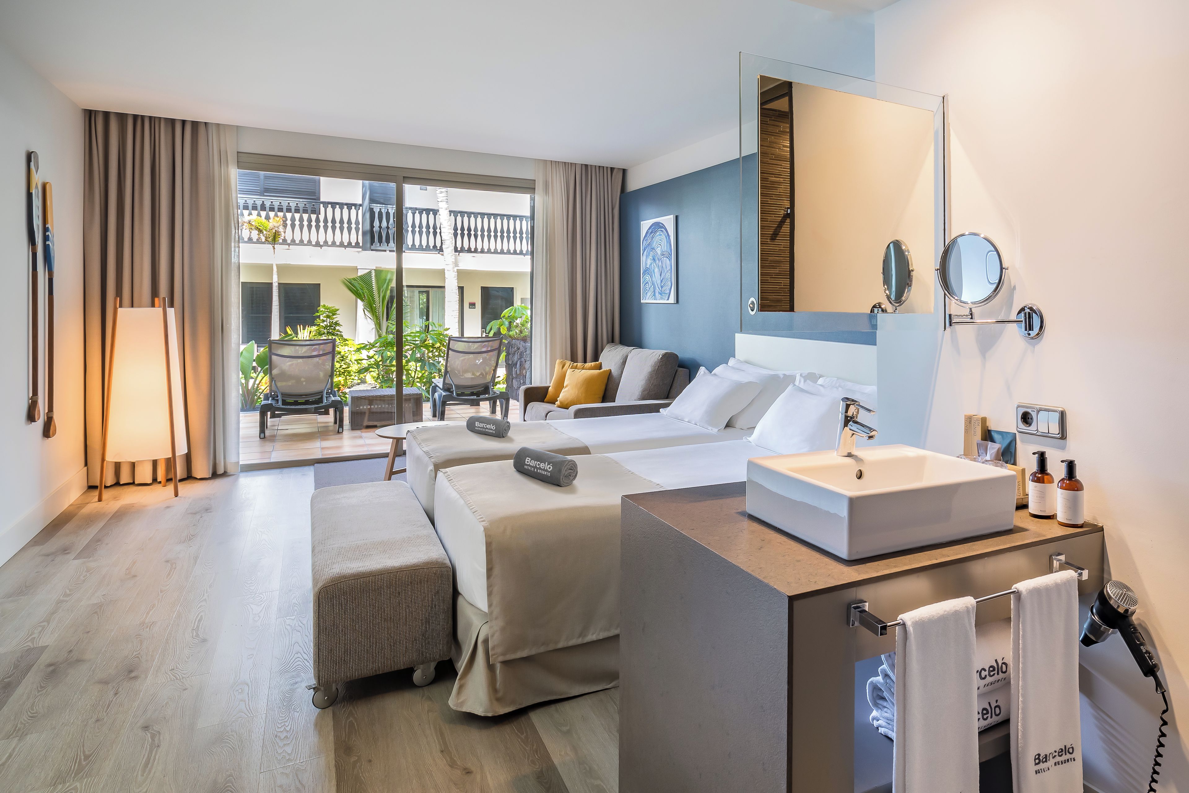 A hotel room with a balcony, a bed, a desk, and a bathroom.
