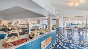 Uma área de buffet com diversos tipos de comida e piso revestido de azulejos.