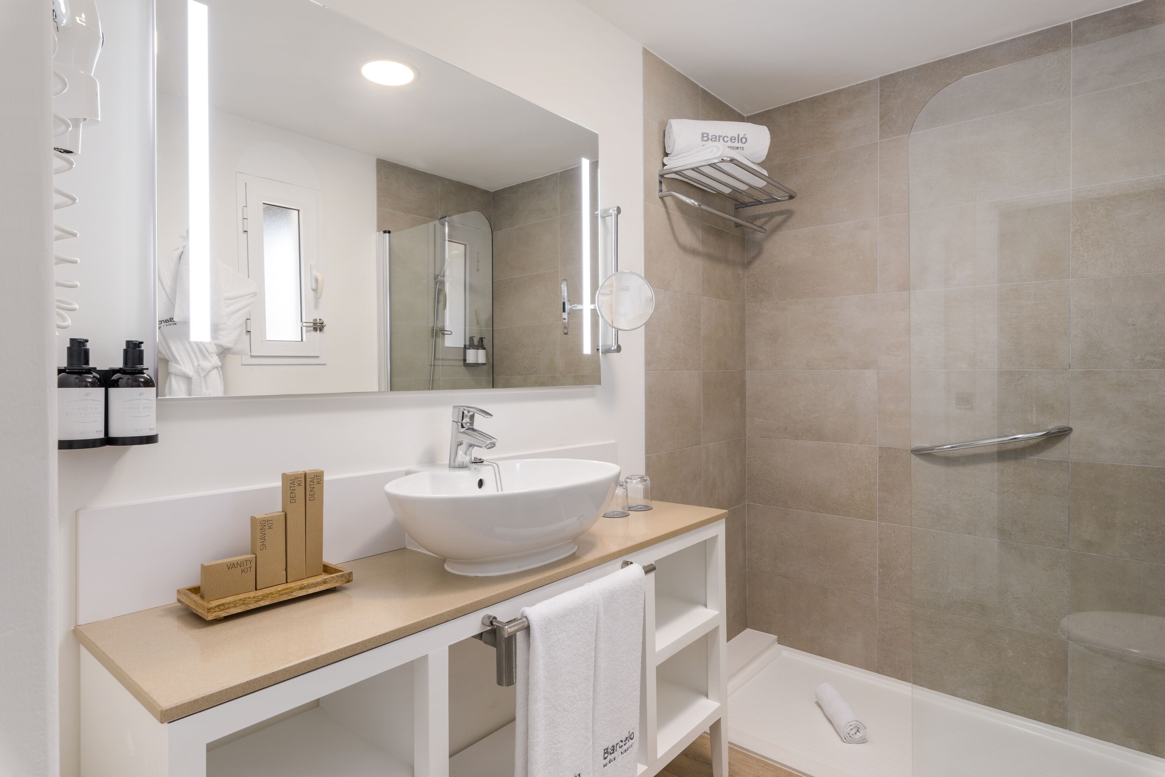 A modern bathroom with a large mirror, white sink, vanity, and a walk-in shower.