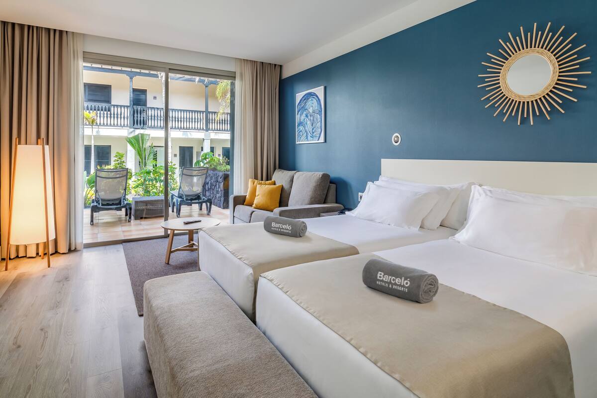 Ein Hotelzimmer mit zwei Betten, einem Balkon und Blick auf die Außenansicht des Gebäudes.