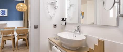 Een moderne badkamer met een groot wastafel, een spiegel en een haardroger bevestigd aan de muur.