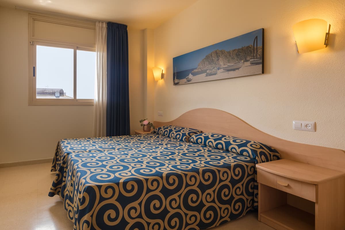 Une chambre à coucher avec un lit, une table de chevet et un tableau au mur.