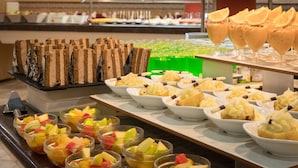 Buffet com diversos itens de comida, incluindo saladeiras de frutas, sobremesas em camadas e uma variedade de pratos.