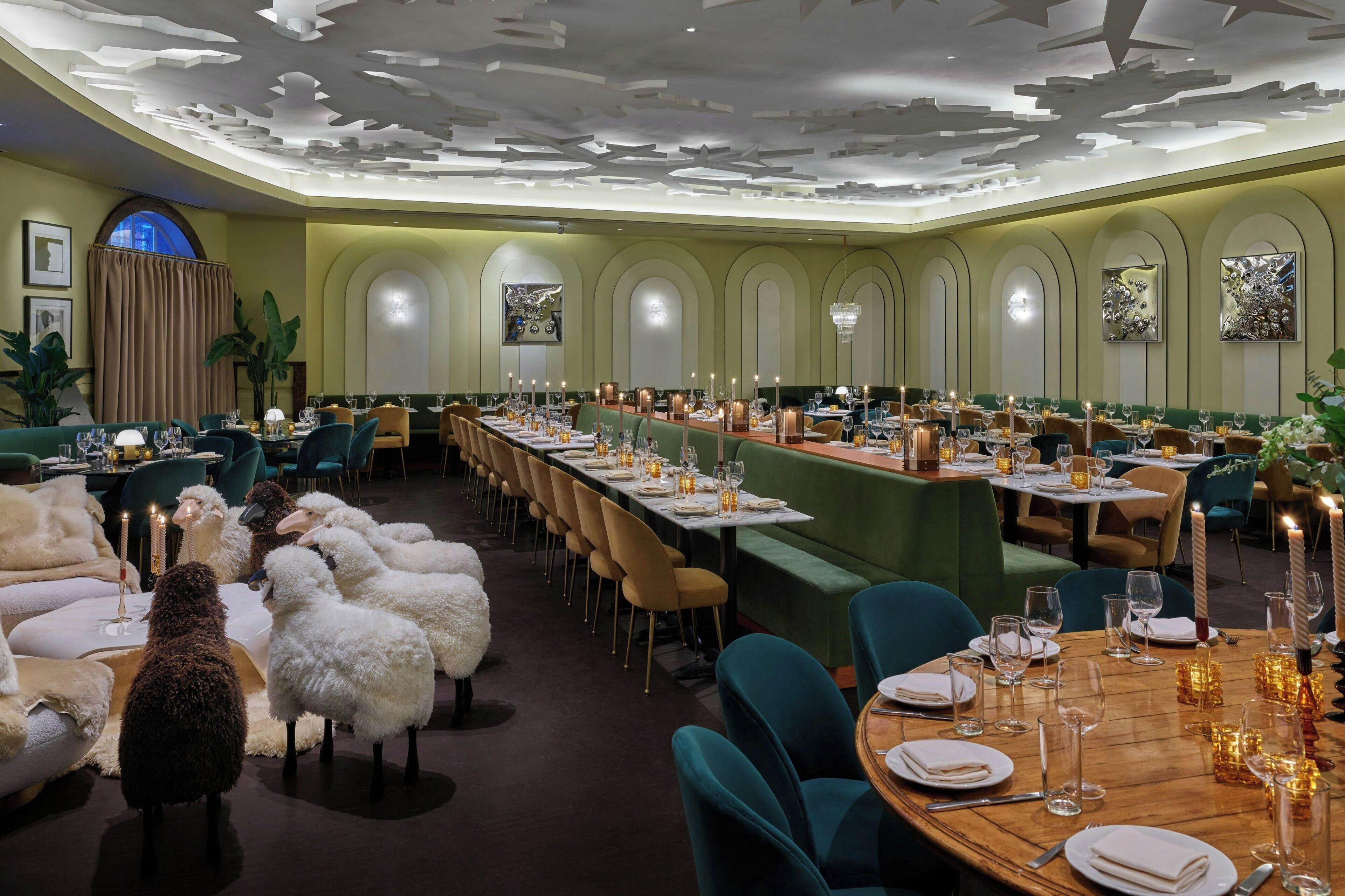 A formal dining room with long tables, green upholstered chairs, and a decorative ceiling.