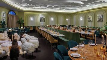 A formal dining room with long tables, green upholstered chairs, and a decorative ceiling.