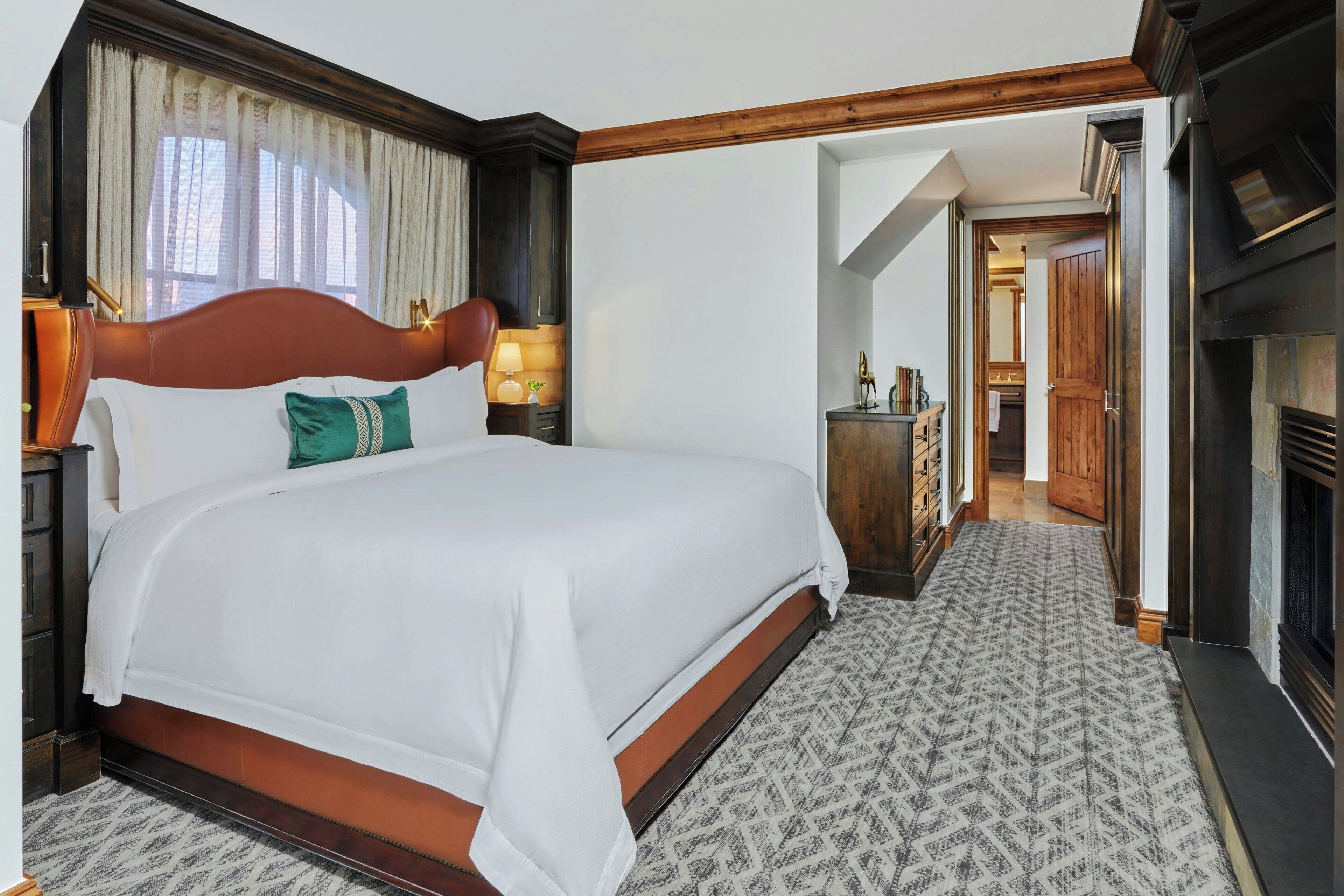 A large bed with a wooden headboard, white bedding, and a patterned rug.