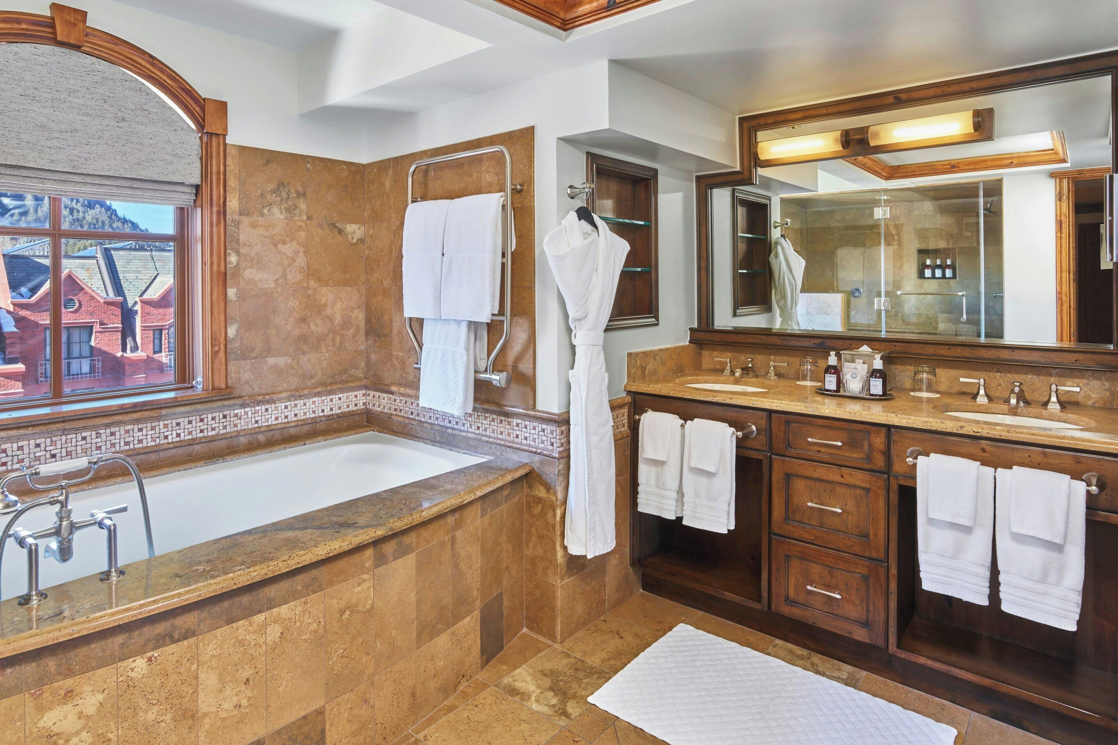 A modern bathroom with a large bathtub, dual sinks, and a large mirror.