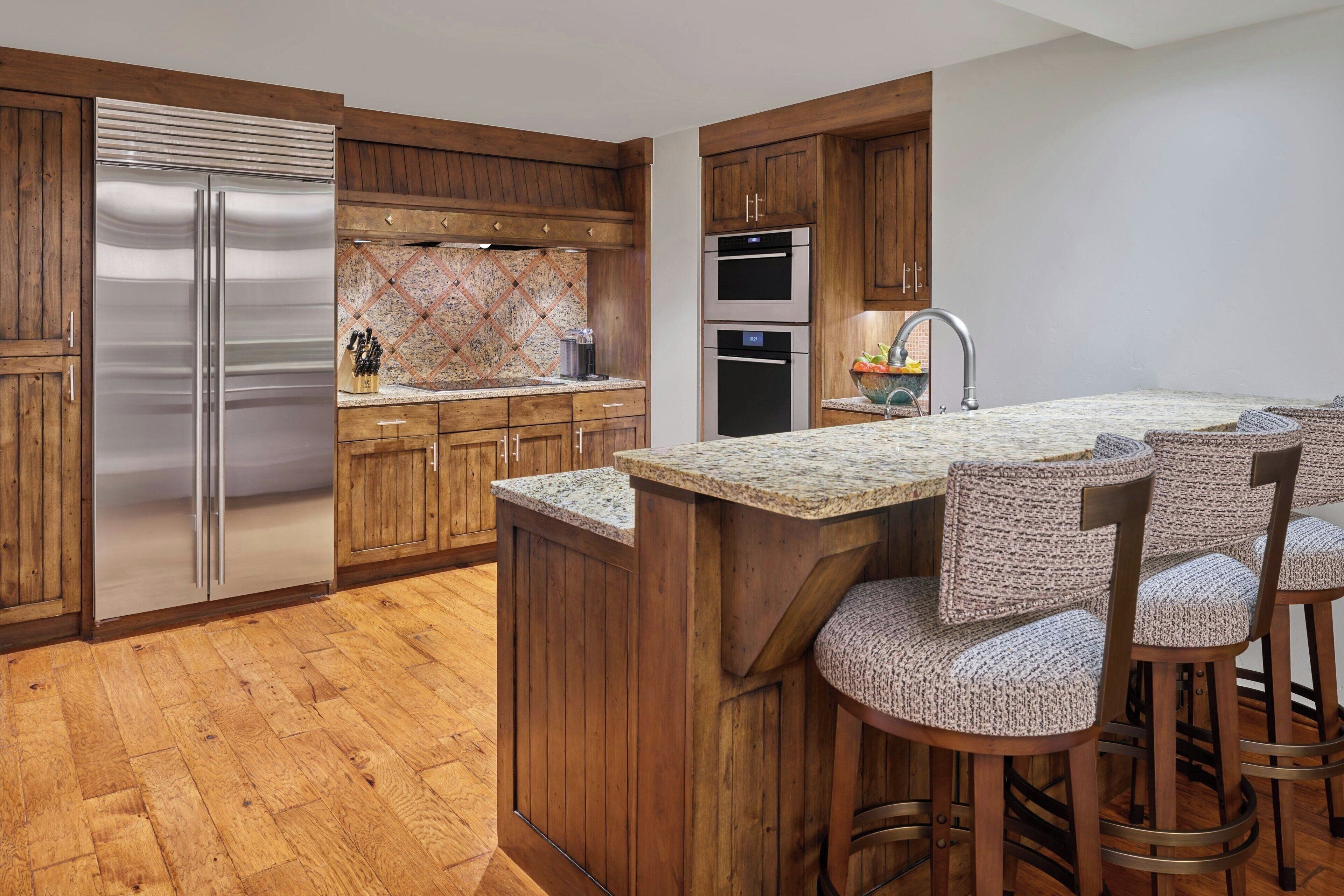 A modern kitchen with wooden cabinets, stainless steel appliances, and a granite countertop.