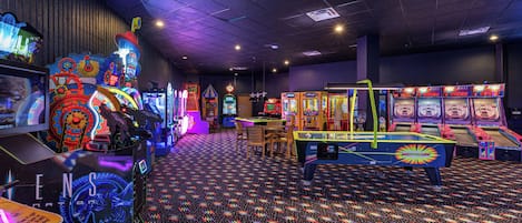 Una habitación con máquinas de videojuegos, una mesa de ping pong y un suelo con diseño.